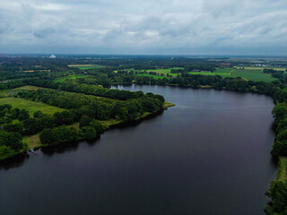 Aerial view of a lake surrounded by trees under a cloudy sky, aerial photograph of Lake Tweelbäker in Oldenburg, with the city of Oldenburg in the background, Germany