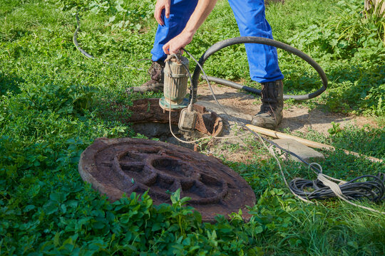 pumping out sewage with a drainage pump, man pumps out sewage from a cesspool in the backyard, service for cleaning a septic tank and sewage from a house