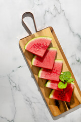 Juicy watermelon slices on rustic board evoke summer solstice picnics and refreshing Halcyon Days, garnished with vibrant mint leaves