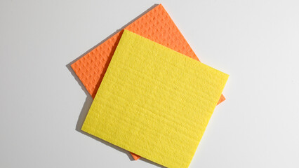 Boldly vibrant sponges, poised atop each other, echo spring cleaning rituals and the tactile...