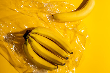 Ripening bananas bask dramatically on sheer plastic waves, embodying tropical abundance and Wrapping Day's quirky, fruity revelry