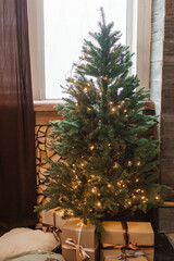 Designer Christmas tree decoration with lights. The concept of celebrating New Year and Christmas. Gifts in craft packaging under the Christmas tree.