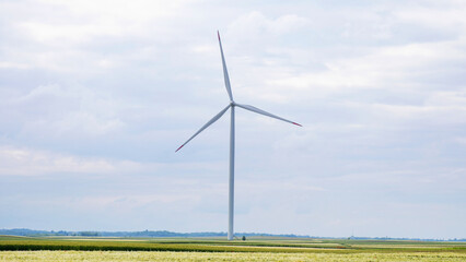 Silent wind turbine dominates vast fields, evoking Earth Day's renewable whispers and the ethereal charm of Sustainability Week