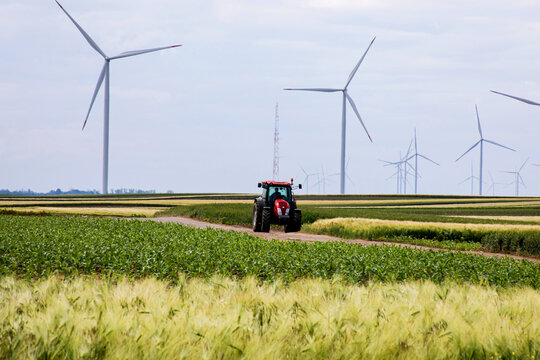 Rumbling tractor in lush green fields, sustainable agriculture whispers amid towering wind turbines, capturing Earth Day's eco-resonance