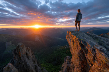 Fototapeta premium Person enjoys sunrise view from rocky peak in mountainous landscape