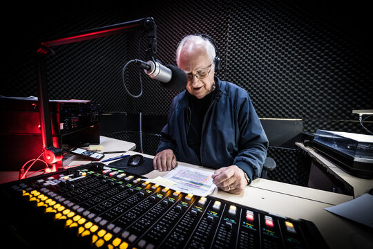 An elderly caucasian man DJs and presents his music show on live radio in Melbourne, Australia
