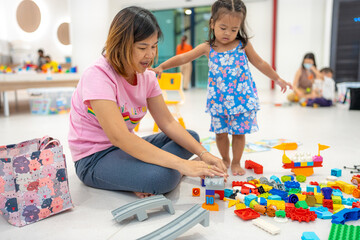 Mom with kids boy and girl learnning build color toy block in classroom