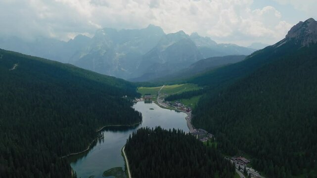 Panoramic aerial view of Lago di Misurina natural alpine lake in Dolomites surrounded by mountains and coniferous forests in evening