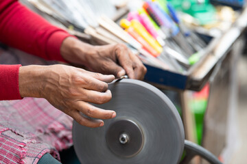 Sharpening knives blade on a whetstone, indian knife sharpener at work, wheel propelled via pedals, culture of India