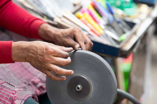 Sharpening knives blade on a whetstone, indian knife sharpener at work, wheel propelled via pedals, culture of India