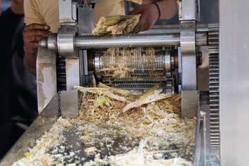 Sugarcane juicing machine on a market stall in India, fresh pressed juice from stalks, squeeze the sweet fruit drink from the cane 