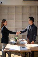A man shakes hands with a woman in a business meeting