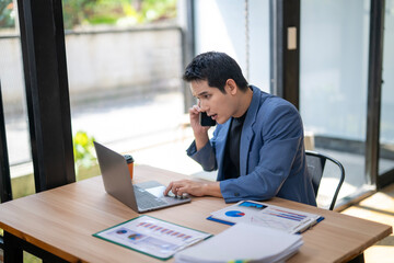 A man is talking on a cell phone while sitting at a desk