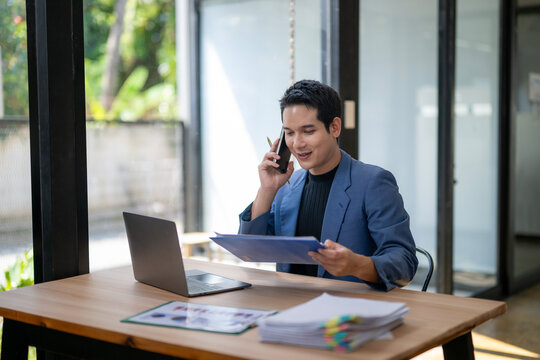 A man is talking on a cell phone while sitting at a desk