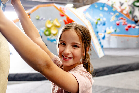 Close-up of young girl holding on the climbing holds of bouldering walls