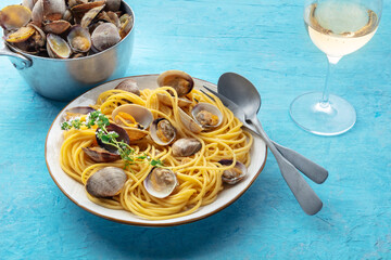 Vongole clams with spaghetti pasta, with white wine. Seafood linguine on a blue background