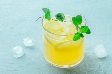 A glass of lemonade, a mocktail with lemon juice, on a blue background, summer cold drink, with...