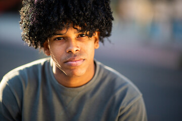 Latin young man with curly hair gazing calmly at the camera