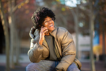 Smiling man talking on phone while sitting outdoors in winter clothes
