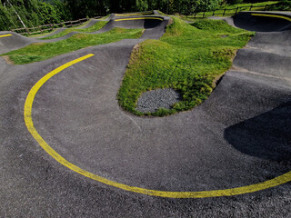 bike path in the car park Pumping (moving up and down) is used instead of pedaling and bouncing to move bicycles, scooters, skateboards and inline skates along large yellow pumptrack track