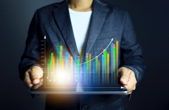 Data analysis concept with businessman holding tablet to show data on screen as bar chart growth display and rising up represent revenue increase