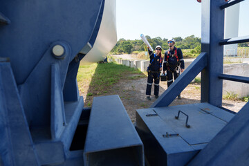 An engineer carefully examines a wind turbine blade at a construction site, placing a large blade...