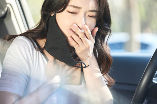 Young Woman Sitting in Car Removing Black Face Mask and Taking a Deep Breath Through the Window