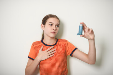 Young girl using asthma inhaler on studio white background