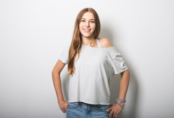 Obraz premium Portrait of teenage girl in casual t-shirt on light background in studio.