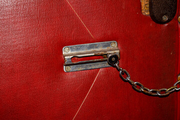 Old Door Chain Lock on Red Leather Upholstered Door — Vintage Security Lock, Interior Safety Element, Retro Hardware, Home Entrance Protection