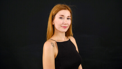 A chest-up headshot of a young, brown-haired woman taken in a studio setting with a black background