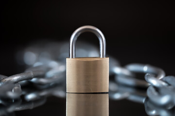 A solitary padlock on a reflective surface evokes concepts of security, isolation, and control....