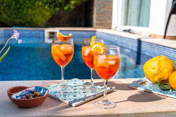 Refreshing summer drink by the pool with fresh oranges and snacks
