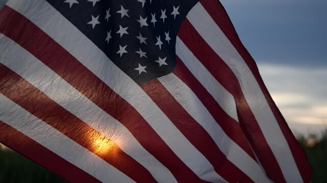 Close up USA American flag waving in the sky against sunset, sunrise outside background. Concept Fourth of July, 4th of July, Independence Day, Veteran Day, Holiday, Celebration. Freedom, Celebration