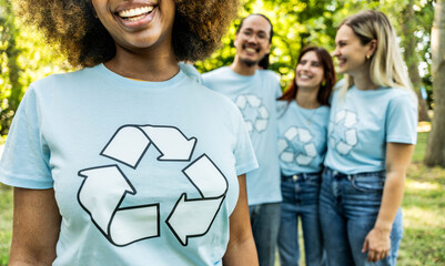 Multi ethnic group of volunteers cleaning up a forest together - Happy team of environmental activists smiling together outdoors - Environmental protection and non profits organization concept