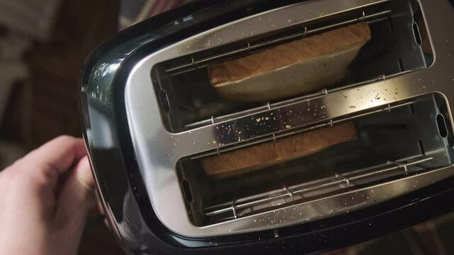 Girl turns on toaster pressing lever down bread slices slowly lower from top view kitchen scene.