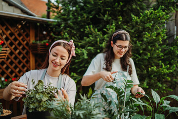 Two female friends or sisters taking care of plants with water can and mister	
