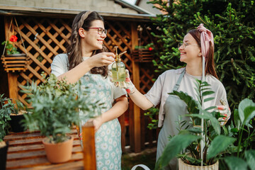Two female friends or sisters taking care of plants with water can and mister	
