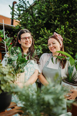 Two female friends or sisters taking care of plants with water can and mister	
