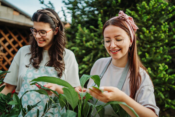 Two female friends or sisters taking care of plants with water can and mister	
