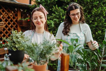 Two female friends or sisters taking care of plants with water can and mister	
