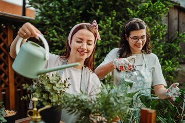 Two female friends or sisters taking care of plants with water can and mister	
