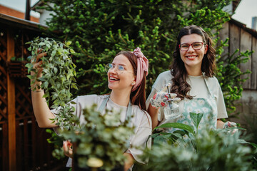 Two female friends or sisters taking care of plants with water can and mister	
