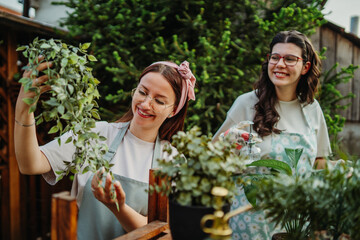 Two female friends or sisters taking care of plants with water can and mister	
