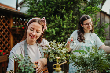 Two female friends or sisters taking care of plants with water can and mister	
