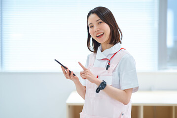 スマートフォンを持つ白衣とエプロン姿の女性