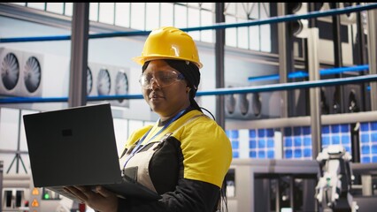 Woman working in industry 4.0 plant using notebook, following maintenance procedures. Smart factory...