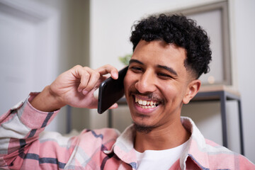 Smiling Man Engaged in a Friendly Phone Conversation at Home