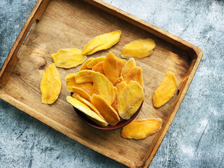 Dried mango strips in wooden bowl. Sliced, dehydrated mangoes. Juicy tropical  fruit with yellow  color.
