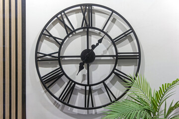 Black Round Clock at Wall With Large Roman Numerals Home Decoration